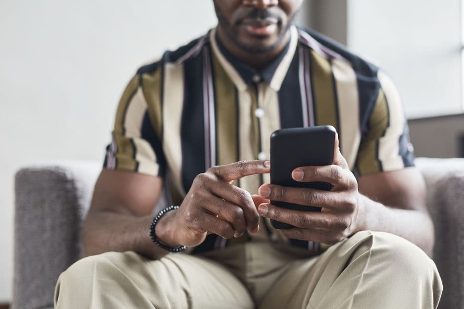Close-up of an African American man using a smartphone indoors.
